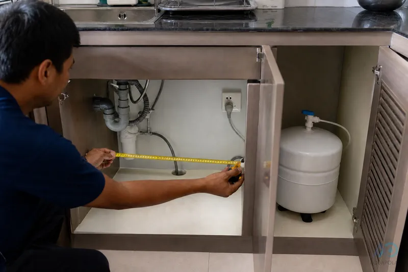 Technician measuring under-counter space for an RO unit and tank